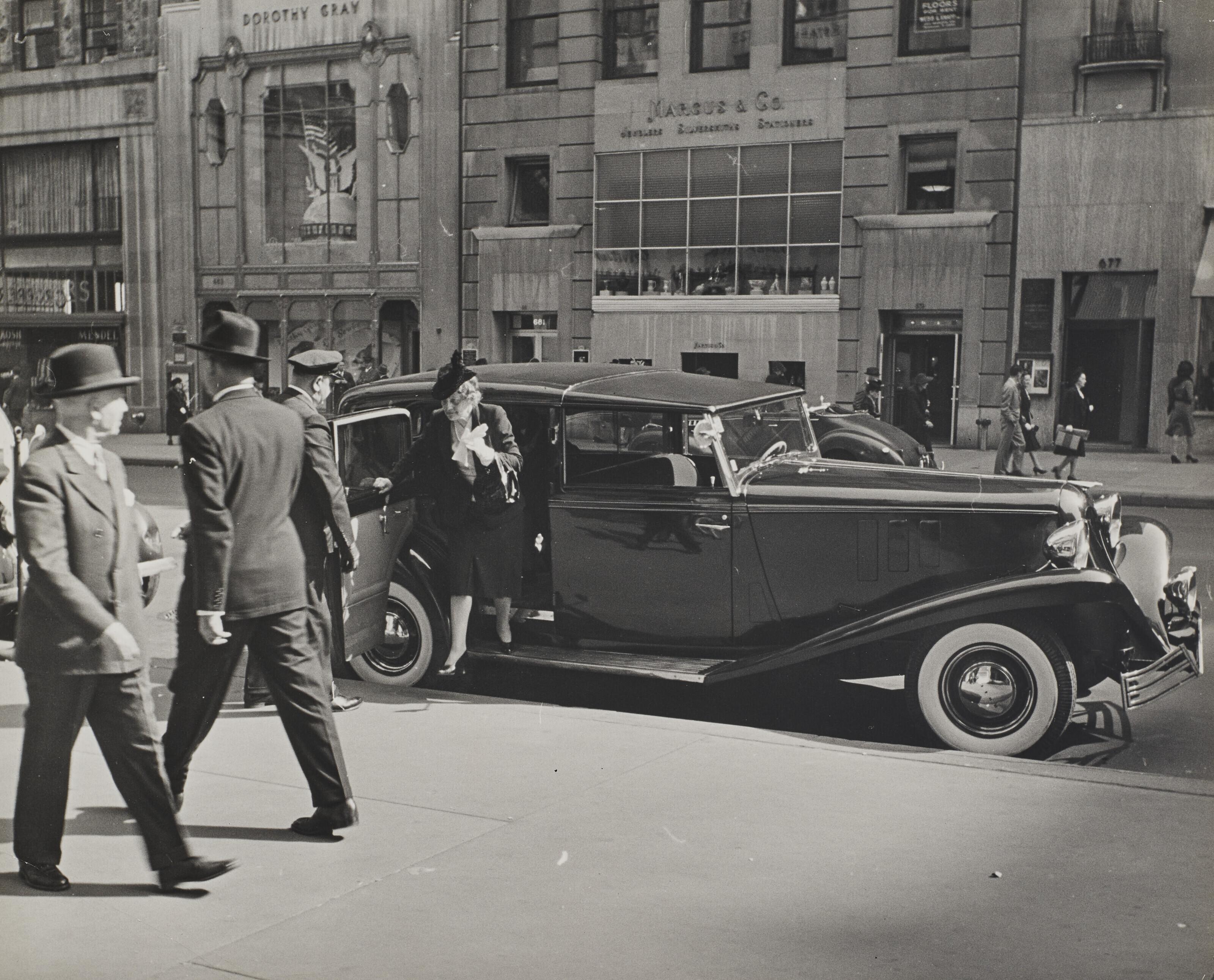 Alfred Eisenstaedt - Chauffeur holding door for matronly woman stepping on to sidewalk on Fifth Avenue in midtown, New York, NY, 1942