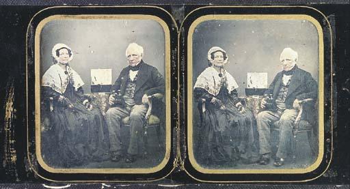 Antoine Claudet - Elderly woman and man, seated by a table with box of stereographs and man holding stereo viewer, 1850s