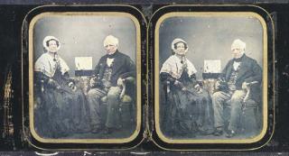 Antoine Claudet - Elderly woman and man, seated by a table with box of stereographs and man holding stereo viewer, 1850s
