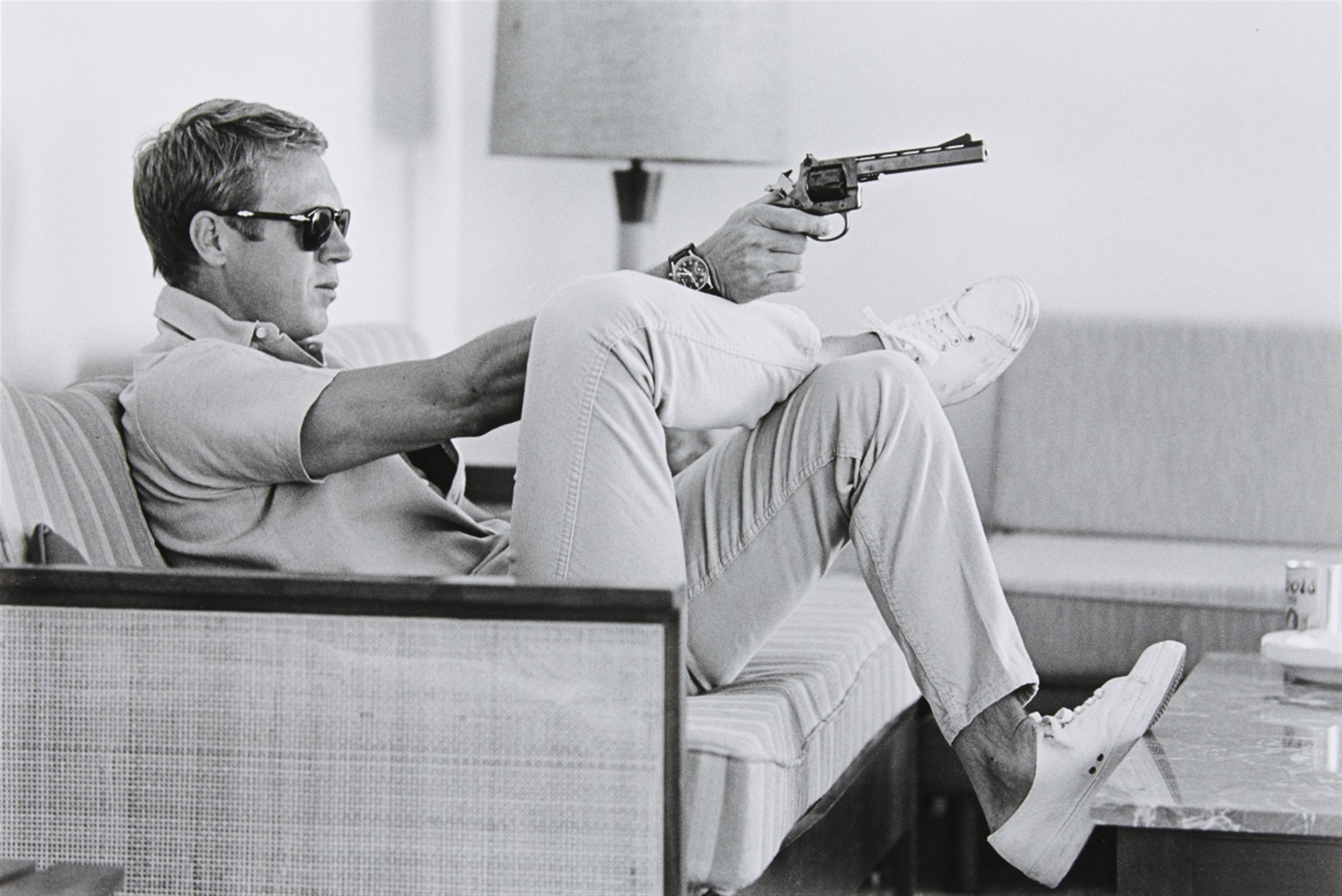 John Dominis - Steve McQueen aims a pistol in his living room, California