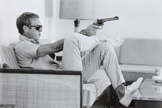 John Dominis - Steve McQueen aims a pistol in his living room, California