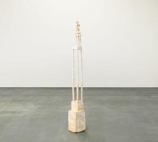 Klaus Hack - Sitzende Figur auf hohem Sockel.