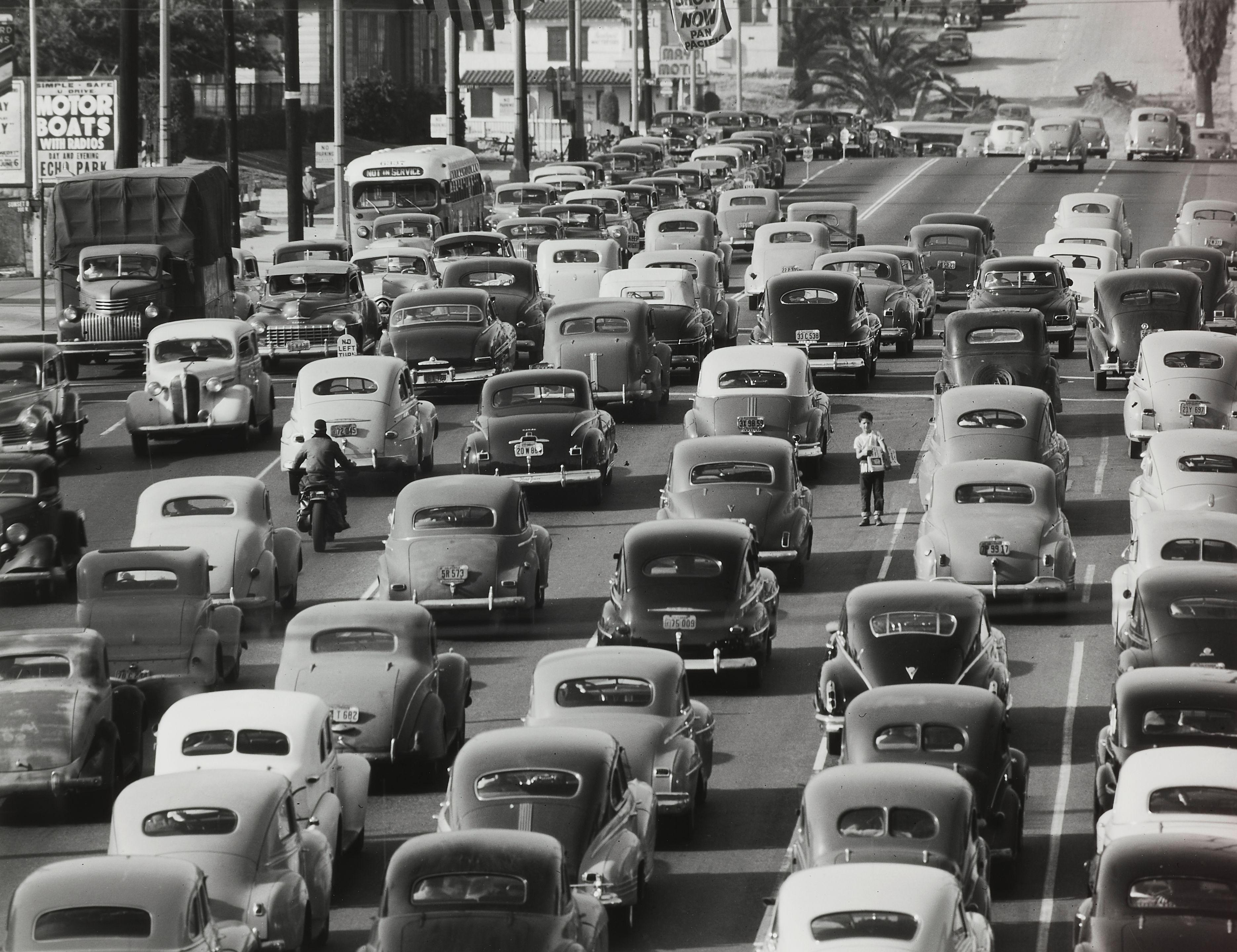 Loomis Dean - Newspaper boy in the middle of Los Angeles traffic, looking south on Olive Street