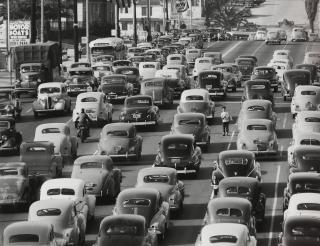 Loomis Dean - Newspaper boy in the middle of Los Angeles traffic, looking south on Olive Street
