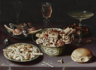 Osias Beert The Elder - A Still Life Of Porcelain Vessels Containing Sweets, Pewter Plates Bearing Sweets And Chestnuts, Three Pieces Of Glassware And A Bread Roll On A Table Draped With A Mauve Cloth