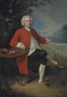 Philip Mercier - Portrait of Ralph Crathorne (d. 1755), of Ness Hall, North Riding, Yorkshire, full-length, seated at a table with grapes, peaches, a riding hat, a hammer and a pruning knife, in a landscape, gesturing to a vinery wall, in a landscape