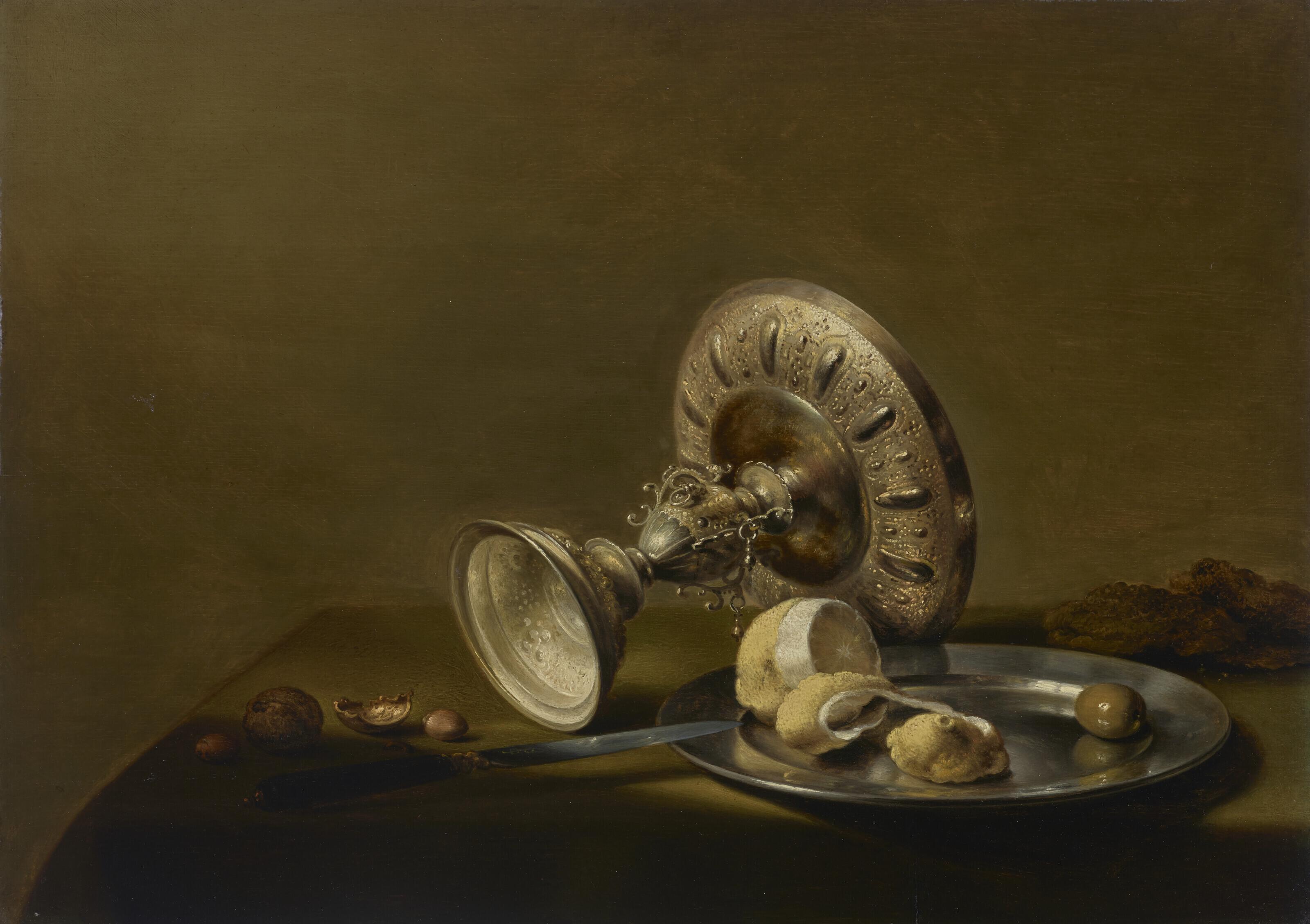 Pieter Claesz - An Overturned Silver Tazza, A Partly Peeled Lemon And An Olive On A Silver Plate, Walnuts, Hazelnuts And A Knife On A Draped Table
